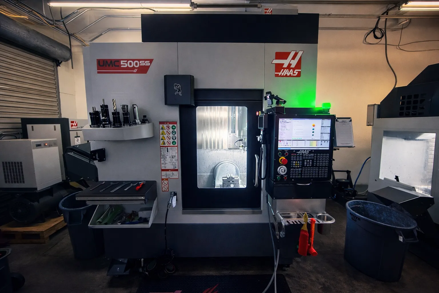 Haas UMC-500SS five-axis machining centre on the Titantech CNC shop floor, mid-cut with the tool changer loaded